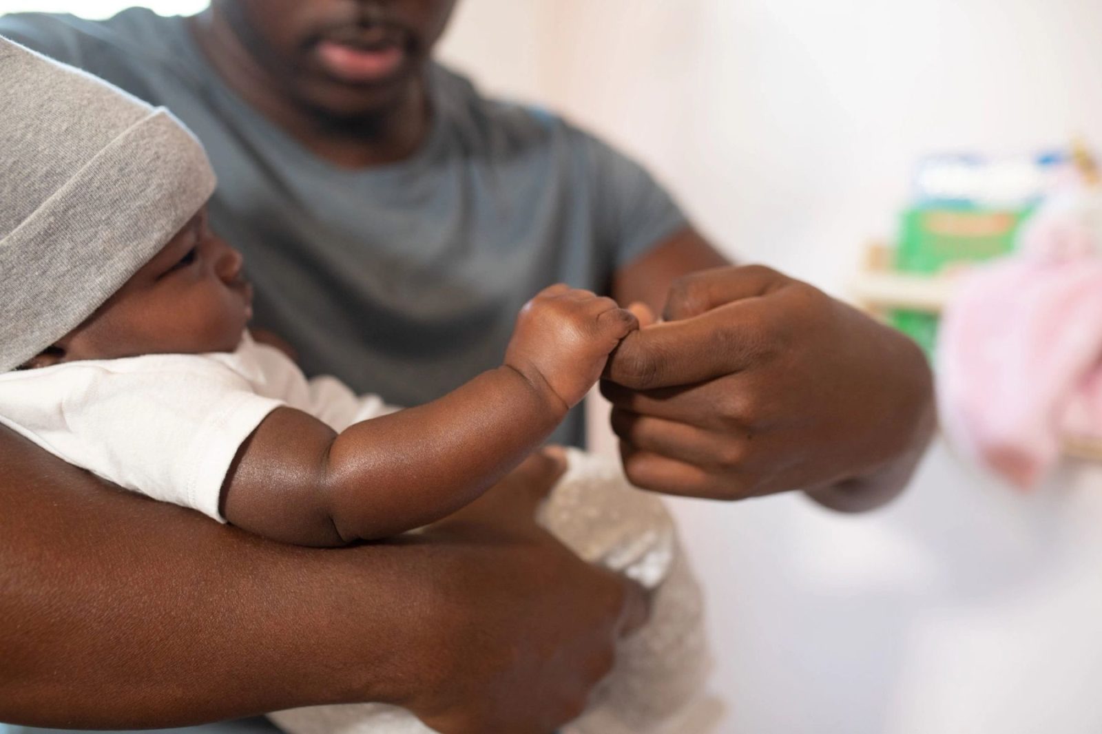A father holding his newborn, the baby gripping his finger